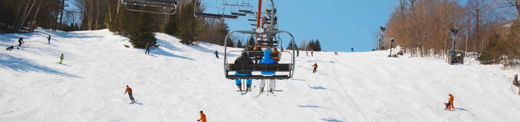 ski lift carrying two people, with people below skiing