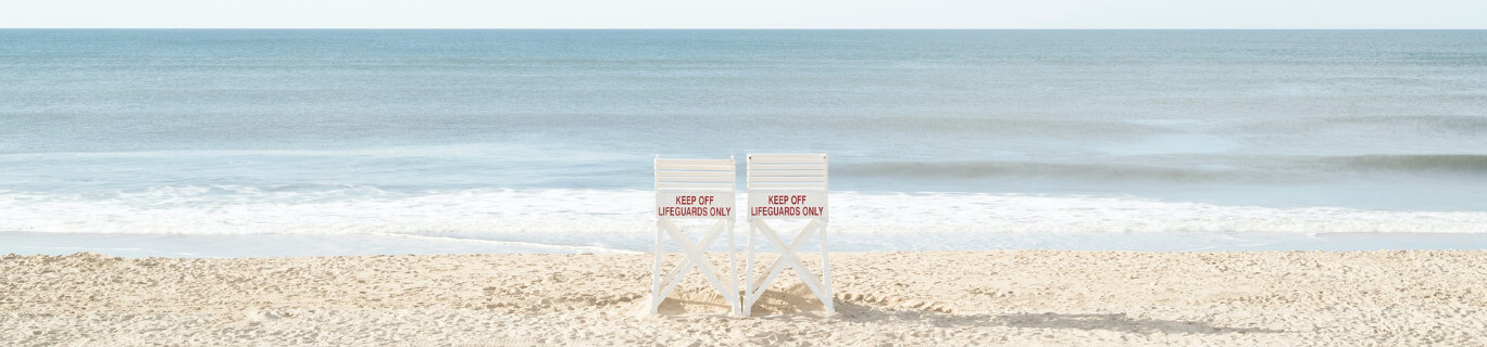 two tall lifeguard chairs on a beach